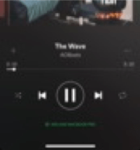 Is an image of the user interface of the application Spotify on a phone, displaying a song playing and the symbol that implies that you are playing in another device through Spotify Connect, in this case a computer.