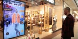 A man tries on Timberland clothes in front of a screen using augmented reality technology at the entrance of the brand's store.